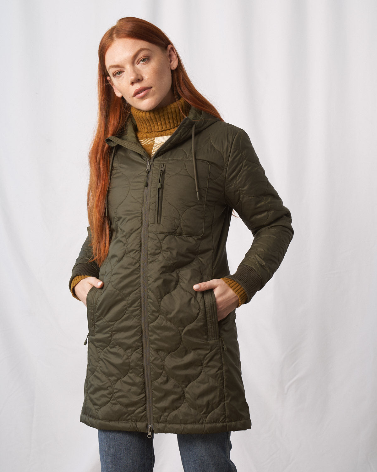 Forest Floor Bison Ultralight Long Liner Jacket (Angle): Olive quilted long jacket with chest zip pocket, worn by woman