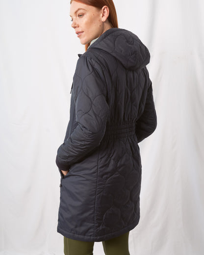 Night Sky Bison Ultralight Long Liner Jacket (Back): Dark navy quilted hooded long jacket with elastic waist, worn by woman