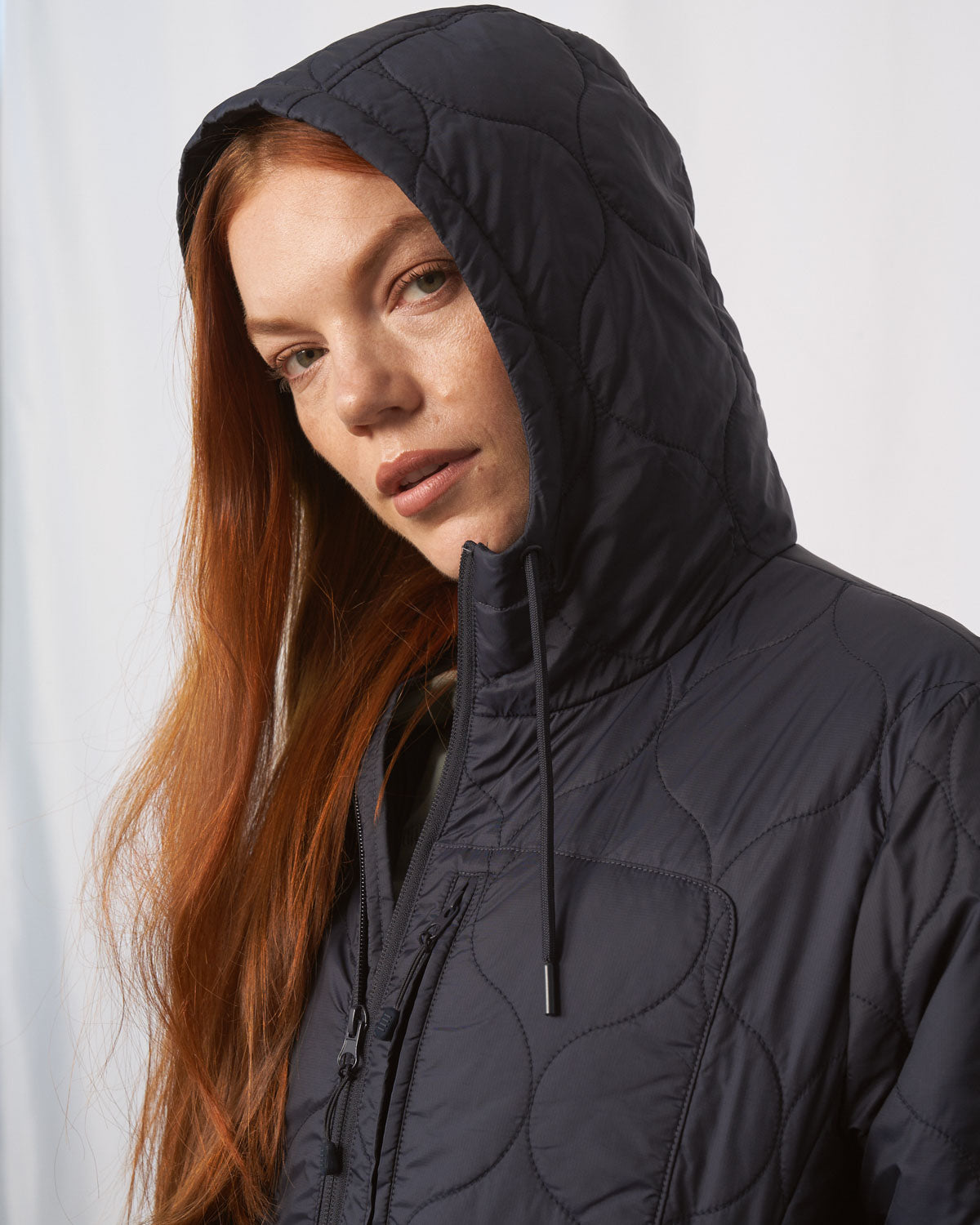 Night Sky Bison Ultralight Long Liner Jacket (Detail): Close-up of dark navy quilted hood with drawstring on a woman