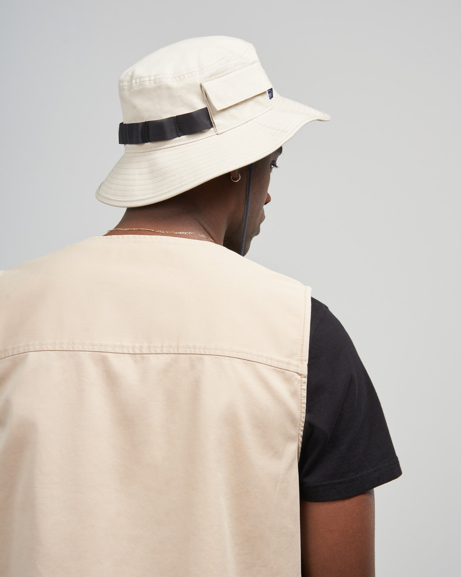 Bone Organic Bucket Stash Hat (In-use): Back view of person wearing cream bucket hat with black webbing strap