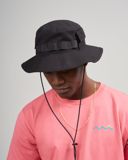 Obsidian Organic Bucket Stash Hat (In-use): Man wearing black wide-brim hat with chin cord and grosgrain band