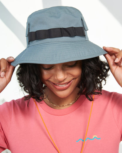 Sky Blue Organic Bucket Stash Hat (In-use): Smiling woman wearing slate blue wide-brim bucket hat with dark ribbon band