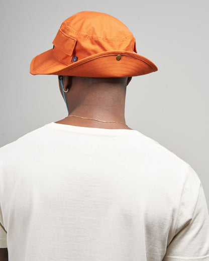 Tangerine Organic Bucket Stash Hat (In-use): Back view of person wearing orange wide-brim hat with gold snap