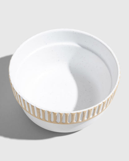 Eggshell Stoneware Stackable Bowl (Angle): White speckled bowl with carved vertical stripe pattern around exterior rim
