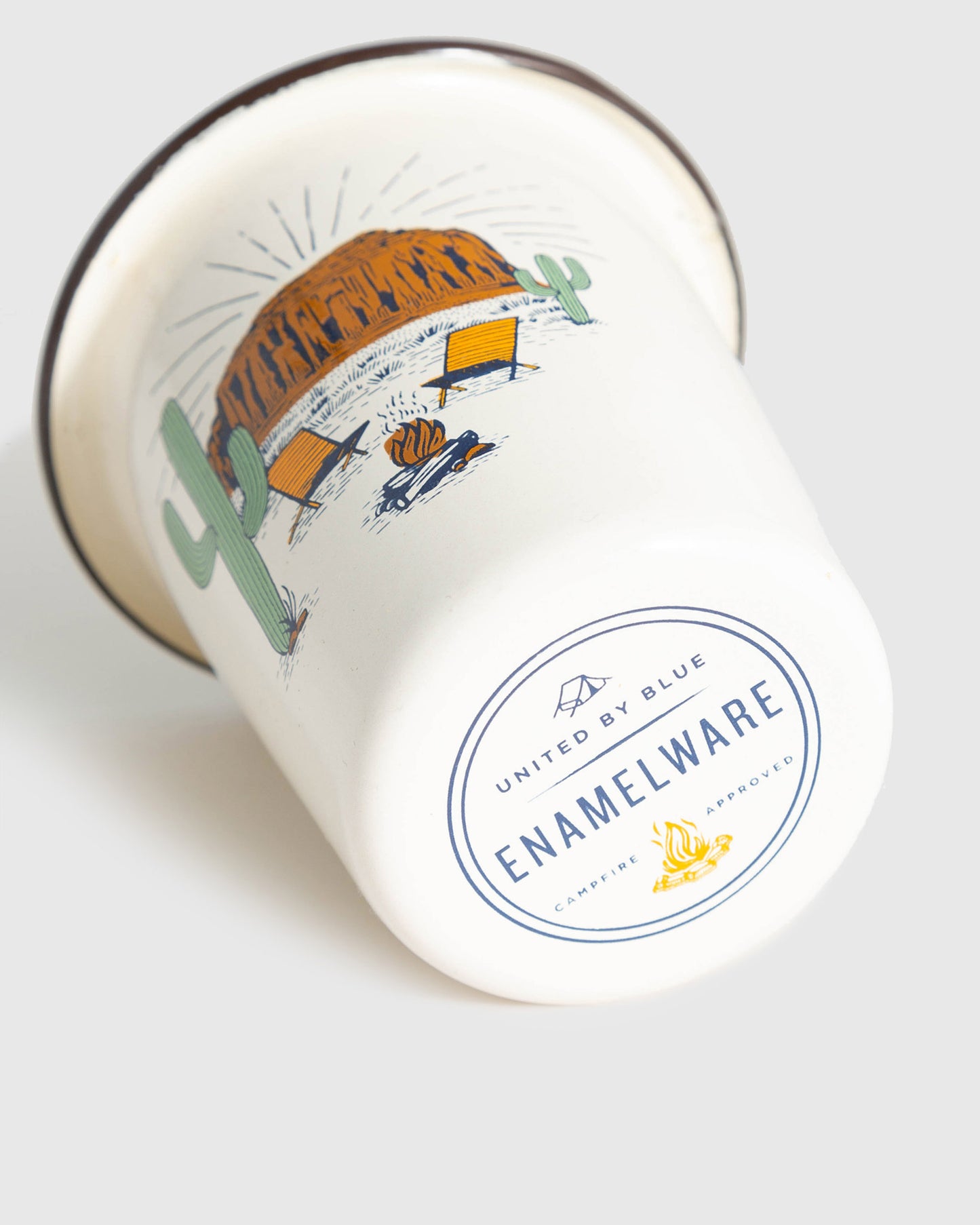 Cream Desert Chill Enamel 12 Oz. Tumbler (Angle): White enamel tumbler tipped on side, desert campfire scene, brand stamp visible
