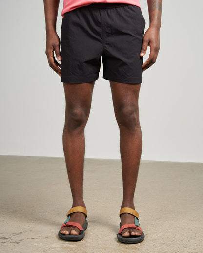 Black Recycled Sport Short (Front): Black elastic-waist shorts on male model with colorful sport sandals