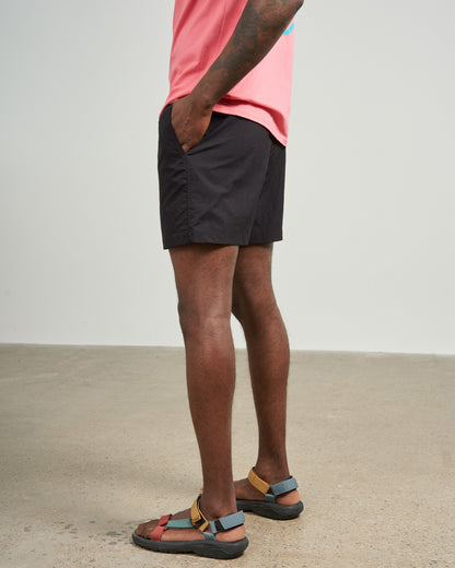 Black Recycled Sport Short (Side): Dark shorts on tattooed model wearing colorful sandals and pink tee