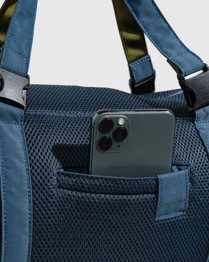 Blueberry (Re)active™ 16L Mini Duffle (Detail): Blue mesh exterior pocket holds a smartphone; tote handles visible above