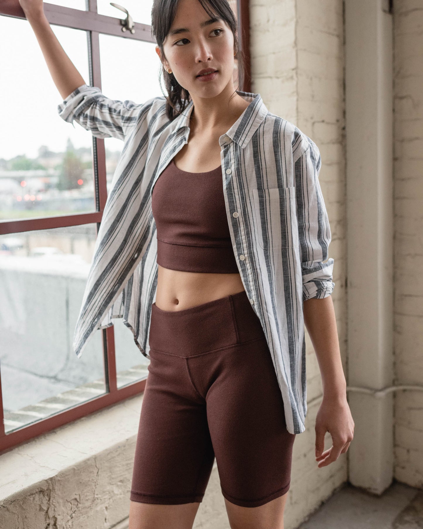 Chocolate EcoKnit™ Ribbed Bike Short (In-use): Dark brown ribbed bike shorts worn by a woman near a window