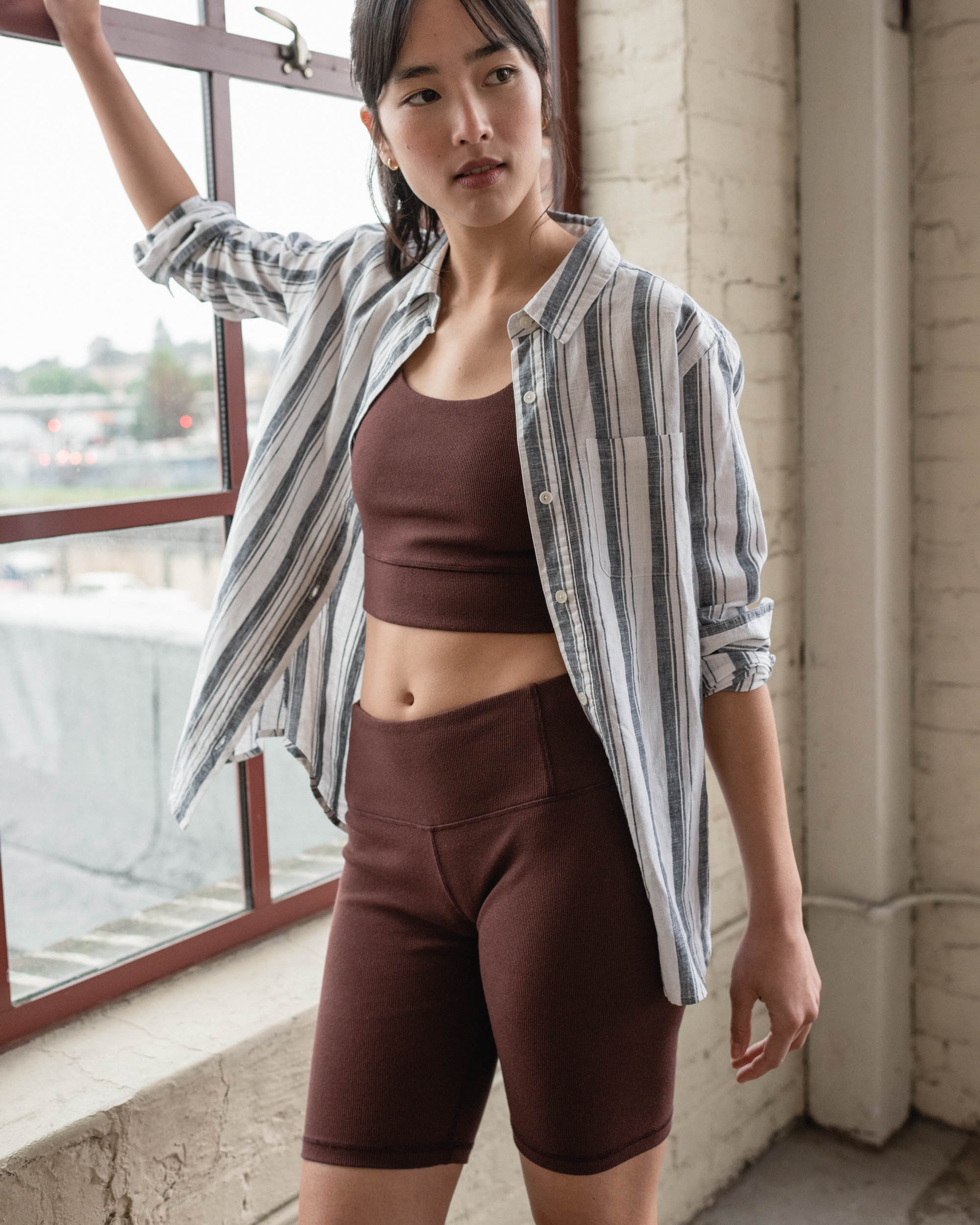 Chocolate EcoKnit™ Ribbed Bike Short (In-use): Dark brown ribbed bike shorts worn by a woman near a window