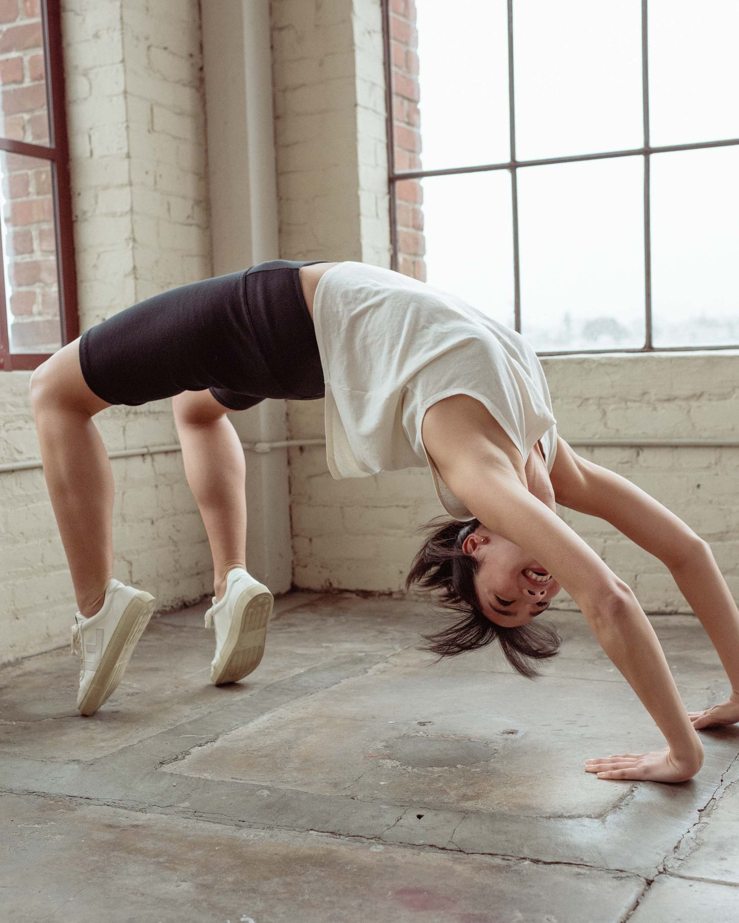 Black EcoKnit™ Ribbed Bike Short (In-use): Person in backbend pose wearing black ribbed bike shorts, white tee