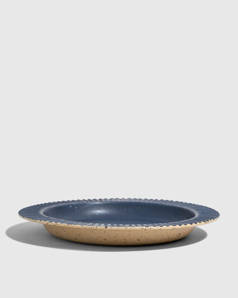 Slate Stoneware Stackable Plate (Angle): Round ceramic dish with ridged rim, matte blue interior, speckled tan exterior