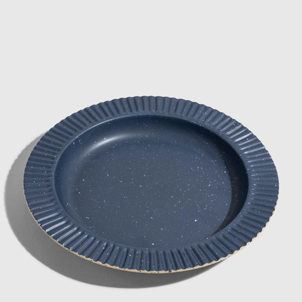Slate Stoneware Stackable Plate (Angle): Round dark blue speckled plate with ridged fluted rim and unglazed edge