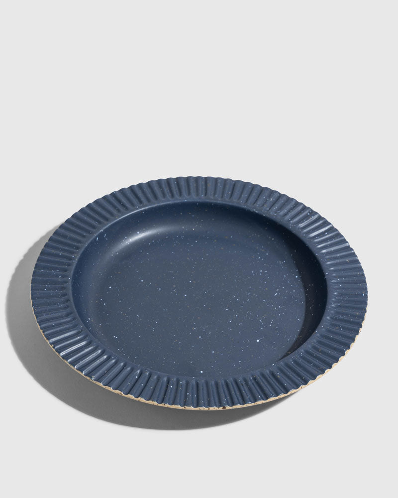 Slate Stoneware Stackable Plate (Angle): Round dark blue speckled plate with ridged fluted rim and unglazed edge