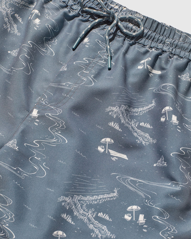 Stone Blue Recycled Swim Trunk - 5" (Detail): Close-up of slate blue fabric with white illustrated beach scene print and drawstring waistband